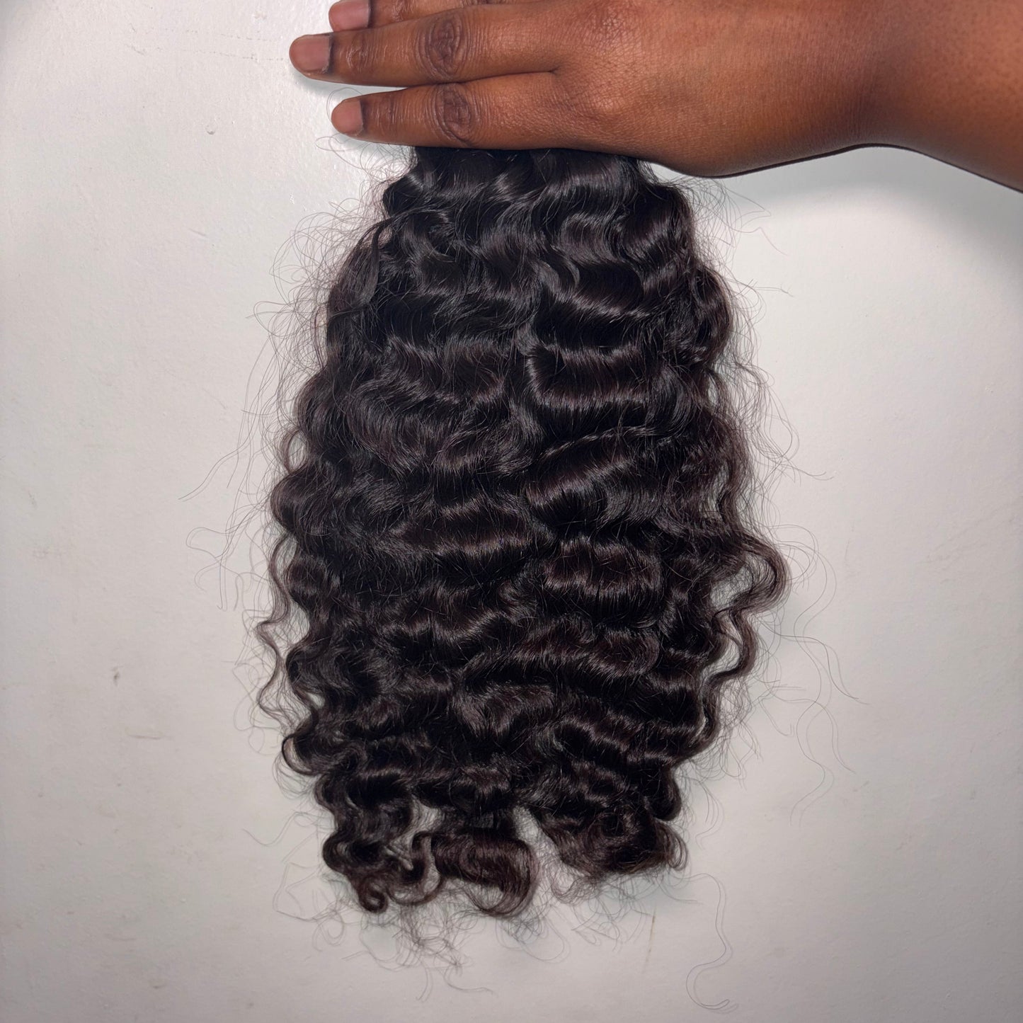 Curly hair extensions on a white background held by hand.