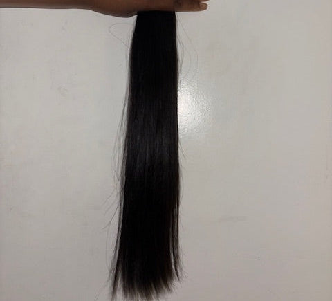 Long black hair strand held by a hand on a white background